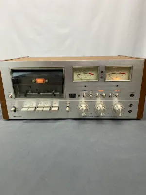 Vintage Pioneer CT-F9191 stereo cassette tape deck featuring a brushed aluminum faceplate, dual VU meters, and a wood-grain cabinet,...