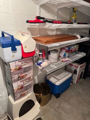 Sale Photo Thumbnail #30: Assorted household and garage items including Igloo coolers, party supplies, a brass bucket, and a Shop-Vac box arranged on wire shelving.