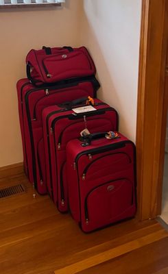 Sale Photo Thumbnail #25: Four-piece American Tourister softside luggage set in red, including three rolling suitcases of varying sizes and a matching duffel bag.