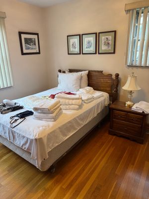 Sale Photo Thumbnail #19: Traditional wooden headboard bed frame with matching two-drawer nightstand, accompanied by framed wall art and a brass-finish table lamp.