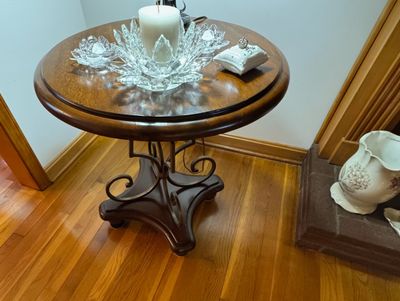 Sale Photo Thumbnail #11: Round wooden accent table with a dark finish, featuring scrollwork metal supports and a sturdy pedestal base.