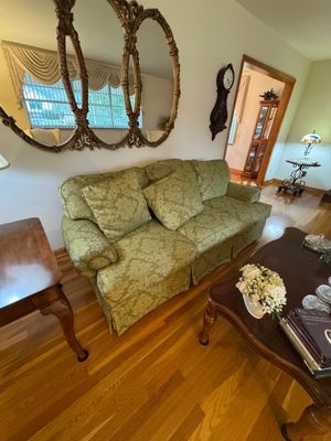 Sale Photo Thumbnail #6: Traditional green damask upholstered sofa with matching throw pillows, paired with a large ornate gold-framed triple-oval wall mirror.