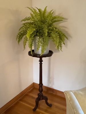 Sale Photo Thumbnail #7: Antique mahogany pedestal plant stand with a turned column and tripod legs, holding a potted faux fern.
