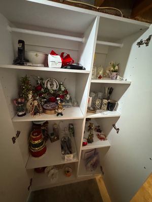 Sale Photo Thumbnail #26: White laminate storage wardrobe filled with various Christmas decorations, figurines, and household items.