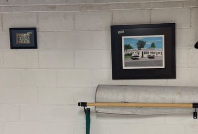 Sale Photo Thumbnail #34: Two framed art prints hanging on a white cinder block wall, including a larger piece depicting a vintage diner scene with classic cars.