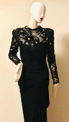 Vintage 1980s black evening gown featuring a ruched bodice, padded shoulders, and a sheer lace yoke and sleeves embellished with gold...