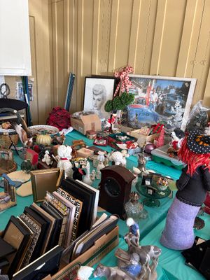 Sale Photo Thumbnail #15: Assortment of vintage collectibles, picture frames, and holiday decor, including a framed Lucille Ball portrait and a Halloween witch doll, displayed on a teal-covered table.