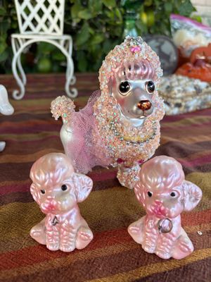 Sale Photo Thumbnail #42: Vintage pink spaghetti poodle figurine adorned with sequins and a tulle tutu, accompanied by two smaller matching pink ceramic poodle figurines.