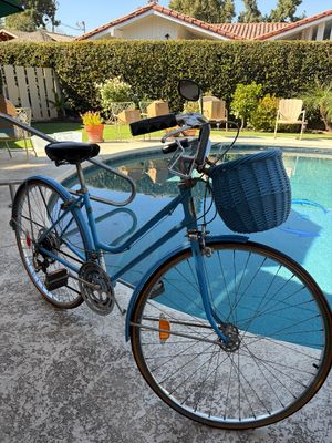 Sale Photo Thumbnail #28: Vintage Schwinn Suburban 10-speed step-through bicycle in sky blue, featuring a front-mounted blue wicker basket and rear-view mirror.