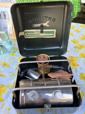 Sale Photo Thumbnail #49: Vintage Optimus No. 111 camp stove in its original green metal carrying case, featuring a brass burner, chrome fuel tank, and included maintenance wrench.