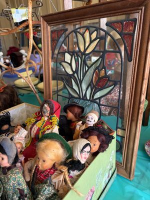 Sale Photo Thumbnail #13: Framed stained glass panel with a floral tulip design, displayed behind a collection of vintage international costume dolls in a decorative box.