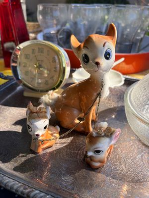 Sale Photo Thumbnail #32: Vintage mid-century ceramic deer family figurine set, featuring a mother deer with two fawns attached by a delicate metal chain, displayed alongside a retro alarm clock on a silver-tone tray.