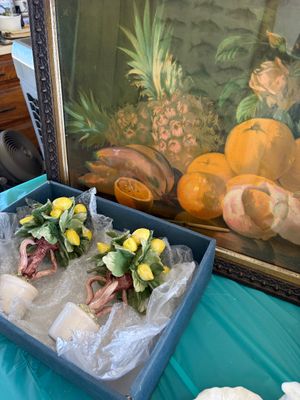 Sale Photo Thumbnail #23: Framed still life oil painting of fruit alongside a pair of ceramic lemon topiary figurines in a storage box.