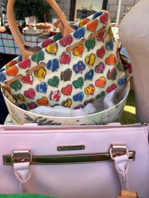 Sale Photo Thumbnail #51: Dooney & Bourke heart-patterned canvas handbag with tan leather handles, displayed alongside a light pink Juicy Couture handbag.