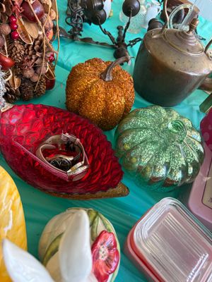 Sale Photo Thumbnail #21: Assorted tabletop decor including a red glass leaf-shaped dish holding wristwatches, decorative pumpkins, and a vintage metal kettle.