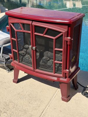 Sale Photo Thumbnail #62: Vintage-style electric fireplace stove in a burgundy finish, featuring double mesh screen doors and faux logs.