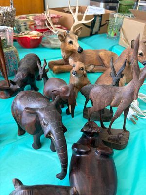 Sale Photo Thumbnail #6: Collection of hand-carved wooden animal figurines, including elephants, deer, and a seal, displayed alongside painted resin deer figures.