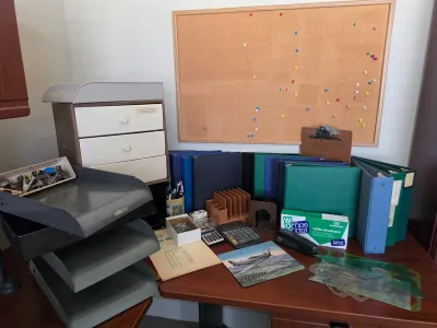 Assorted vintage office supplies including three-ring binders, a cork bulletin board, desk organizers, calculators, and drafting templates.