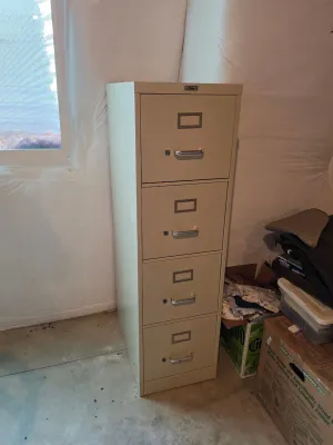 Vintage Peerless four-drawer metal filing cabinet in a beige finish, featuring silver-toned handles and label holders.
