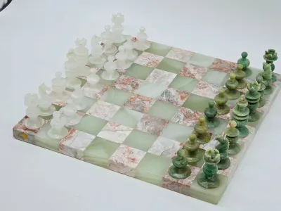 Vintage carved onyx and marble chess set, featuring a green and pinkish-white checkered board with matching hand-carved playing pieces.