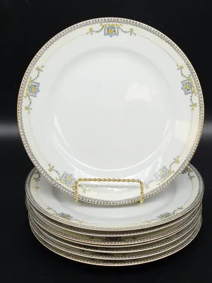 Stack of vintage porcelain dinner plates featuring a delicate yellow and blue floral border with gold-trimmed rims.