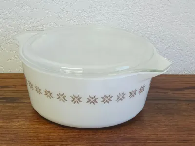 Vintage Pyrex Town and Country pattern round casserole dish with clear glass lid, featuring a brown starburst band on white milk glass.