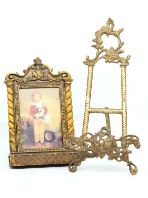 Ornate gold-toned picture frame featuring a print of a young boy with a dog, paired with a matching brass-finished tabletop display easel.