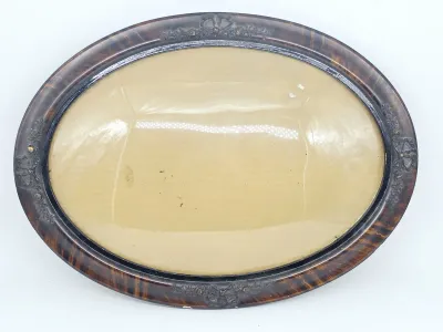 Antique Victorian oval picture frame featuring a tiger stripe wood grain finish, ornate molded floral details, and original convex bubble...