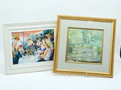 Two framed Impressionist art prints, featuring Pierre-Auguste Renoir's "Luncheon of the Boating Party" in a white frame...