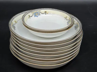 Stack of vintage Noritake porcelain soup bowls and a smaller berry bowl, featuring a delicate cream border with blue and gold swags and...