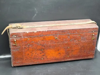 Vintage wooden carrying case with a leather strap, brass hardware, and a distressed finish.