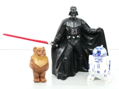 Vintage Star Wars plastic figurines featuring Darth Vader with a red lightsaber, R2-D2, and Wicket the Ewok.