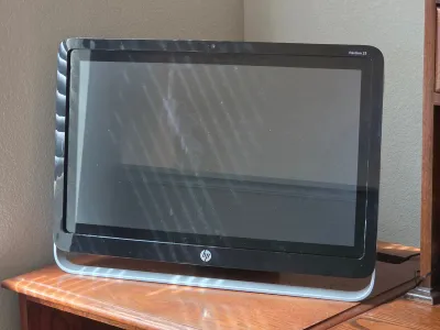 HP Pavilion 23 all-in-one desktop computer with a black bezel and silver stand, showing some light dust on the screen.