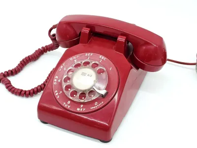 Vintage Western Electric Model 500 rotary telephone in cherry red, featuring a clear plastic dial wheel and matching coiled handset cord.