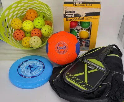 Assorted outdoor games and sports equipment, including a Franklin pickleball paddle with bag, a blue flying disc, a Dave &...