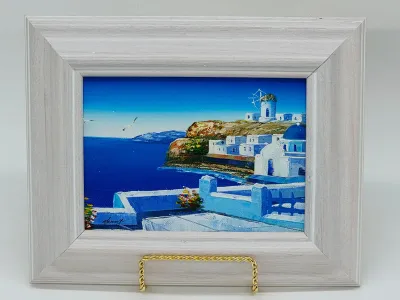 Small oil painting depicting a scenic Greek island landscape with whitewashed buildings and a blue dome, housed in a wide, light-colored...