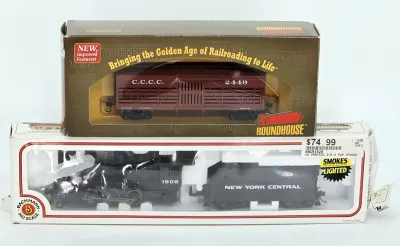 Two HO scale model train cars in their original packaging, featuring a Roundhouse C.C.C.C. stock car and a Bachmann New York Central...