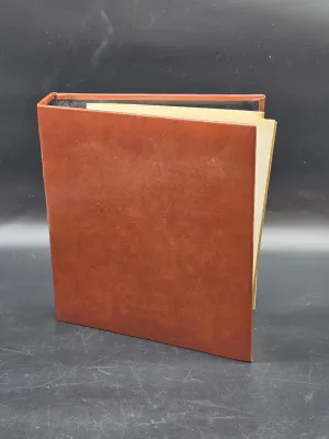 Vintage brown faux-leather binder or photo album, standing upright on a dark surface.