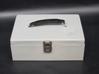 Vintage light gray metal cash box with a black plastic carrying handle and a front latch lock.