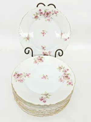 Set of Theodore Haviland Limoges porcelain plates featuring a delicate pink rose pattern, scalloped edges, and gold trim.