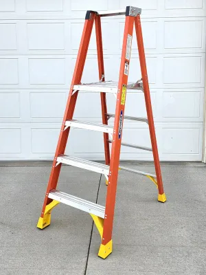 Werner orange fiberglass step ladder with four aluminum rungs and yellow safety feet, showing light wear.