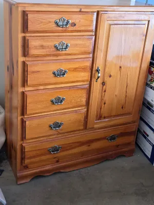 Knotty pine gentleman's chest featuring five stacked drawers, a side cabinet door, and a wide bottom drawer, accented with ornate...
