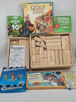 Collection of children's games and activities, including Catan Junior, Guesstures, Pin the Tail on the Donkey, and a wooden block...