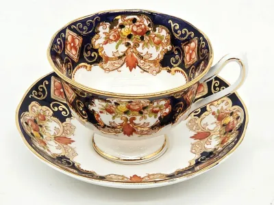 Vintage Royal Crown Derby Imari style teacup and saucer set, featuring cobalt blue, rust, and gold gilt floral patterns.