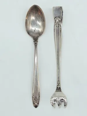 Vintage sterling silver serving spoon and matching sugar tongs, featuring ornate floral and scrollwork details on the handles.