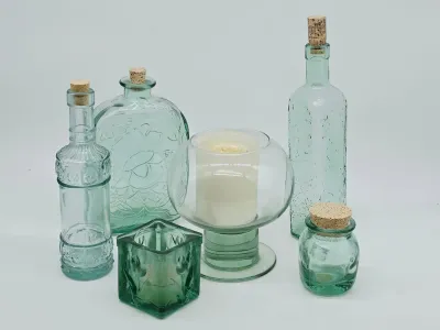 Collection of light green and clear glass decorative items, including four cork-stoppered bottles, a square votive holder, and a pedestal...