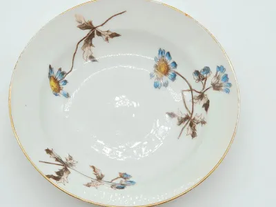 Vintage porcelain bowl featuring hand-painted blue and yellow daisies with brown leaves and a gold-gilded rim.