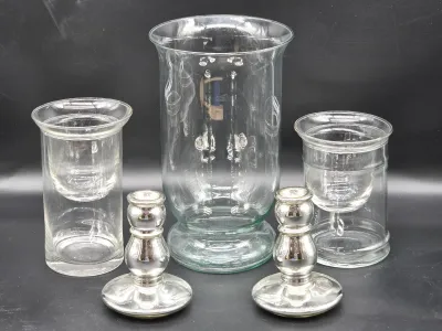 Assorted glassware collection featuring a large central hurricane vase, two smaller glass candle holders with inserts, and a pair of...