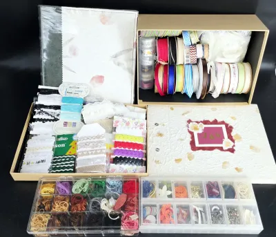 Assortment of crafting and scrapbooking supplies, including ribbons, embroidery floss in organizers, trim, and decorative paper albums.