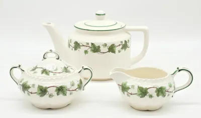 Franciscan Ivy pattern ceramic tea service set, including a teapot, lidded sugar bowl, and creamer pitcher, featuring the classic green...